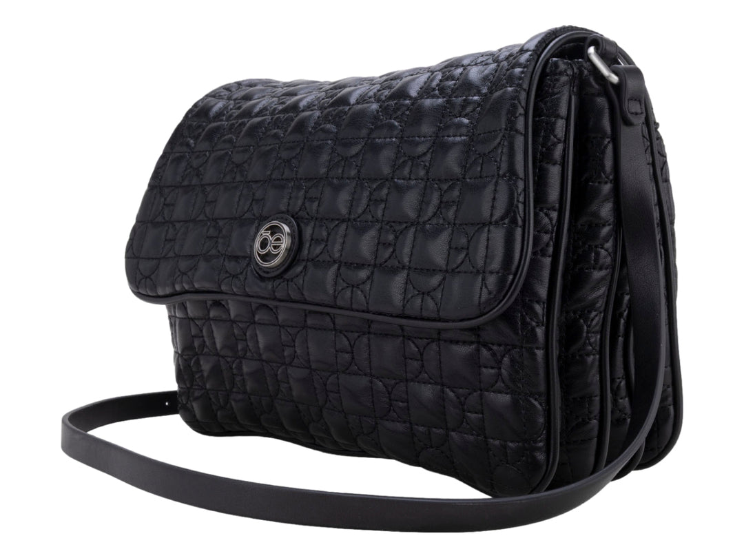 Bolso de hombro color negro con textura acolchada geométrica, correa ajustable y detalle circular central.
