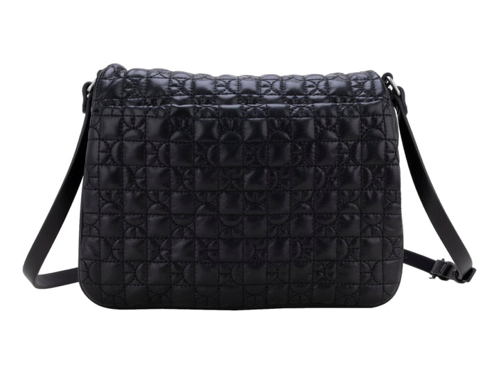 Bolso de hombro color negro con textura acolchada geométrica, correa ajustable y detalle circular central.