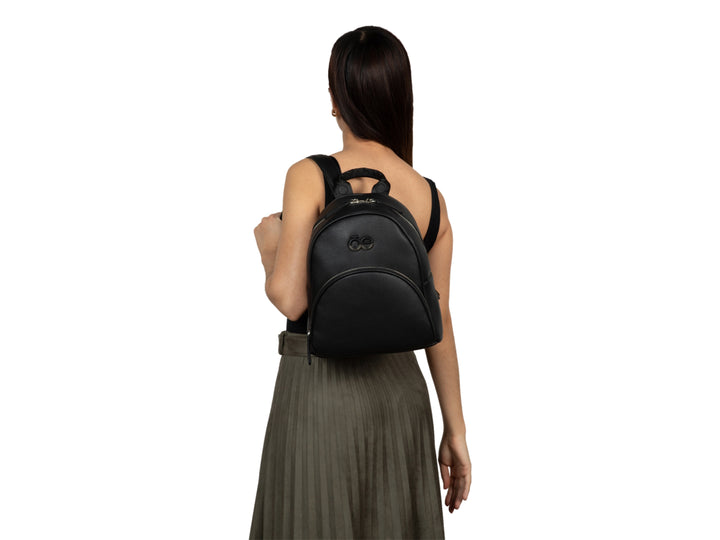 Mochila Cloe de color negro con textura granulada y detalle metálico frontal en forma de infinito.