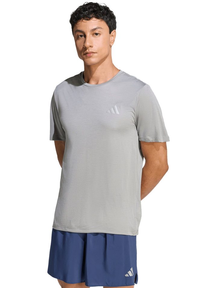 Hombre vistiendo una camiseta deportiva Adidas de color gris jaspeado de manga corta.