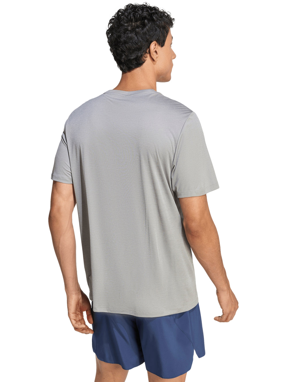 Hombre vistiendo una camiseta deportiva Adidas de color gris jaspeado de manga corta.