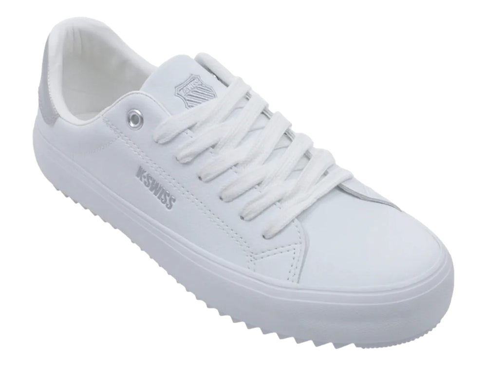 Tenis blancos K-Swiss con detalle plateado en el talón y suela blanca dentada.