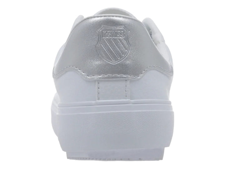 Tenis blancos K-Swiss con detalle plateado en el talón y suela blanca dentada.