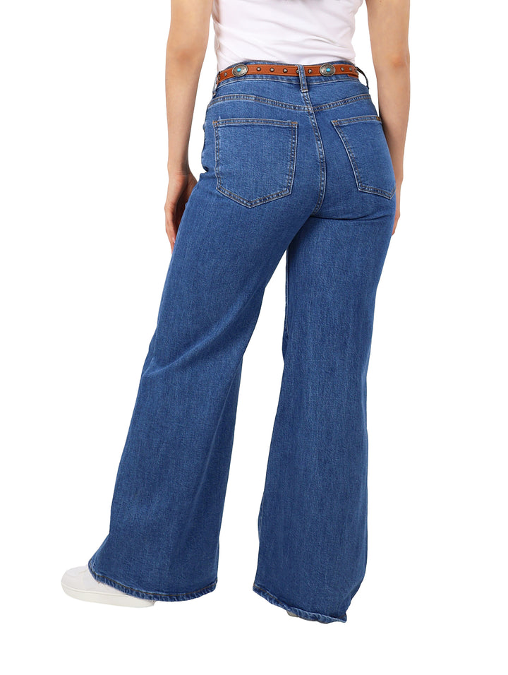 Mujer vistiendo pantalones jeans anchos de color azul con costuras verticales y cinturón marrón.