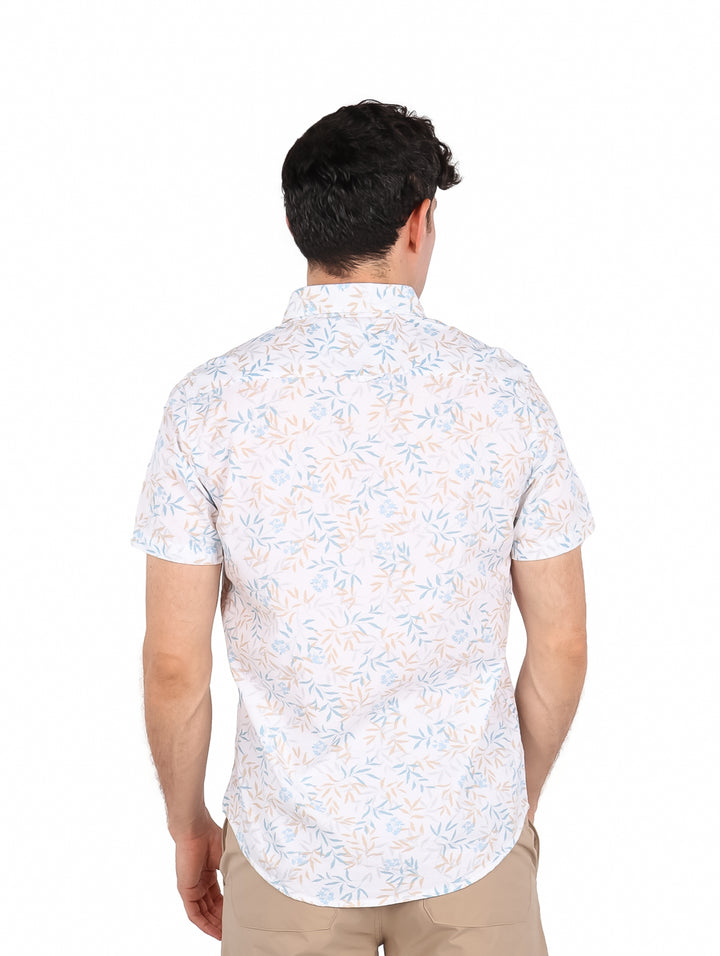 Hombre vistiendo camisa blanca de manga corta con estampado floral en tonos azul y beige.