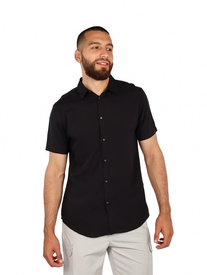 Hombre vistiendo una camisa negra de manga corta con botones y cuello, estilo casual.