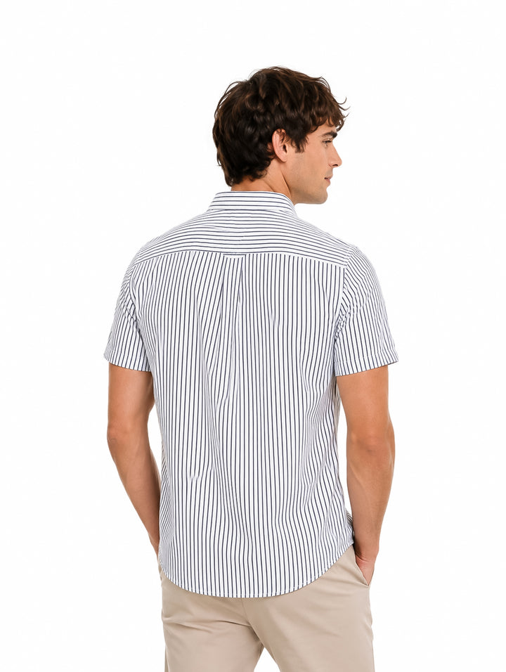 Hombre vistiendo una camisa de manga corta con rayas verticales blancas y azules y pantalones beige.