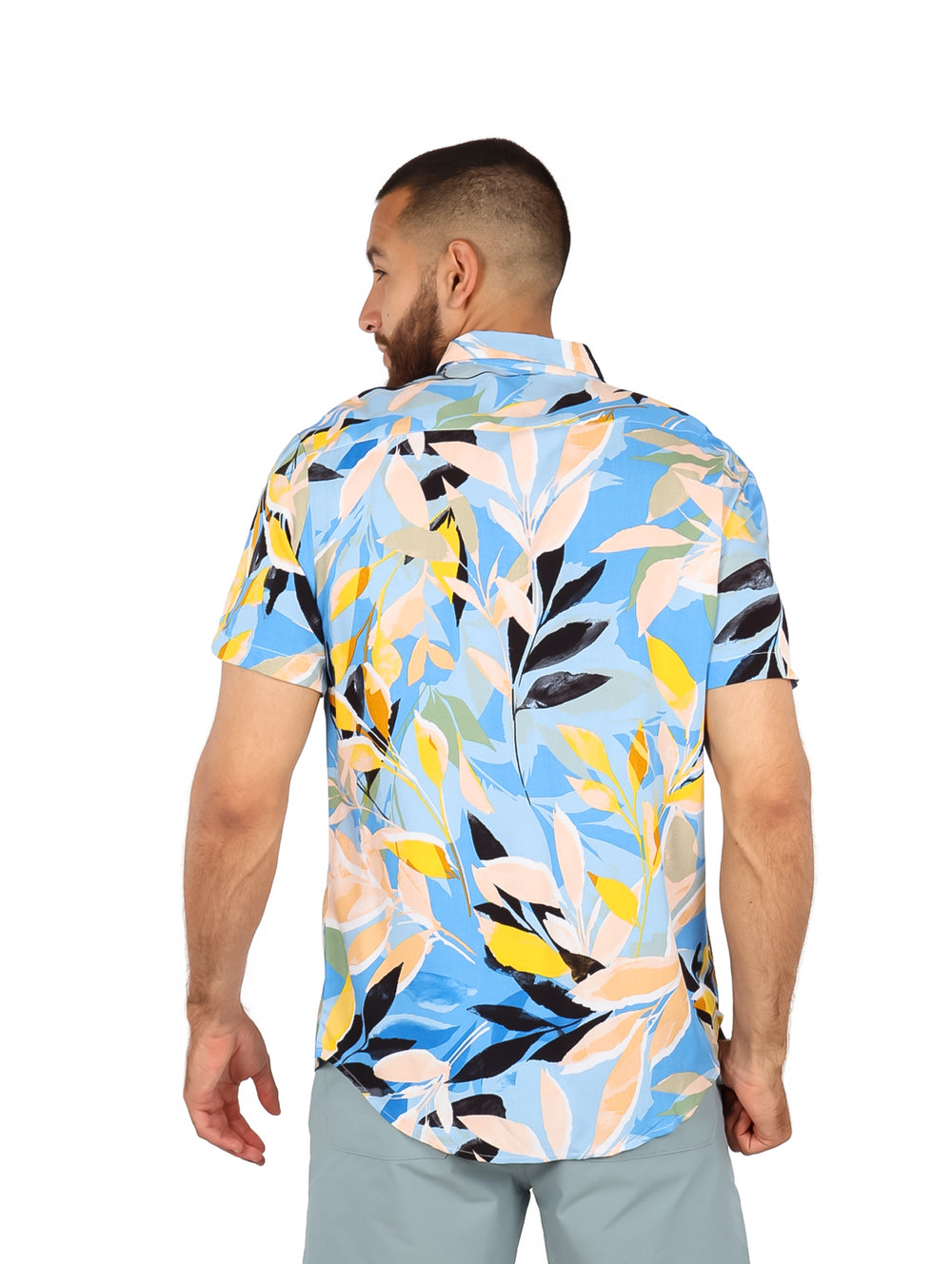 Hombre vistiendo camisa de manga corta con estampado floral multicolor en tonos azul, amarillo y blanco.
