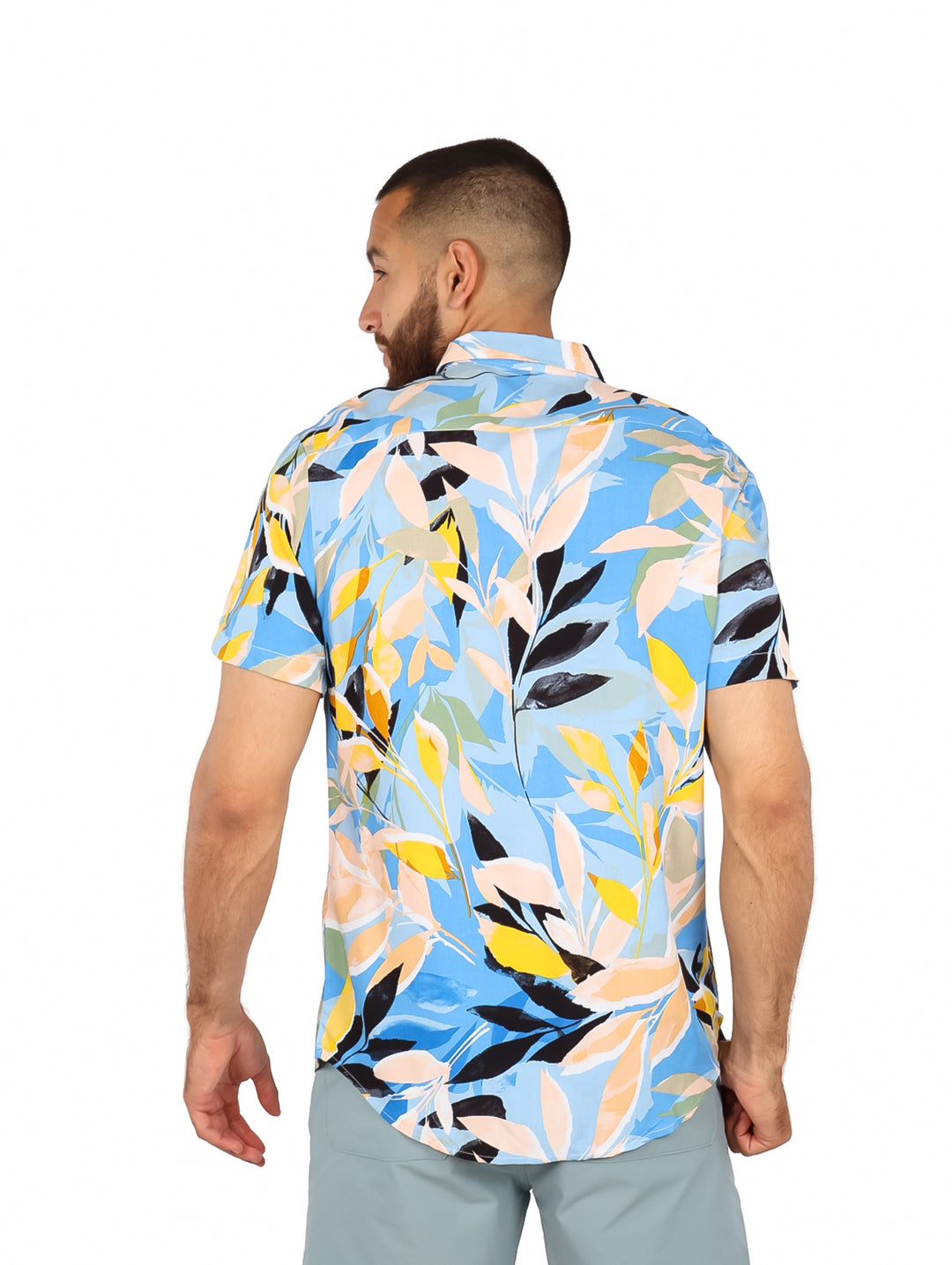 Hombre vistiendo camisa de manga corta con estampado floral multicolor en tonos azul, amarillo y blanco.