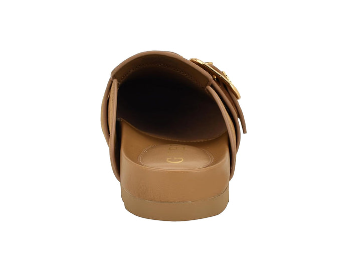 Zapato tipo mule color tan de gamuza con hebilla dorada frontal.