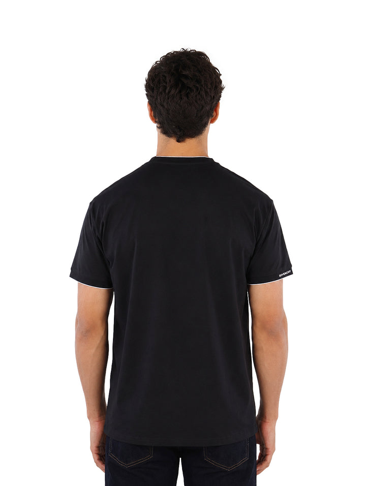 Hombre vistiendo playera Givenchy color negro con detalles blancos en cuello y mangas.