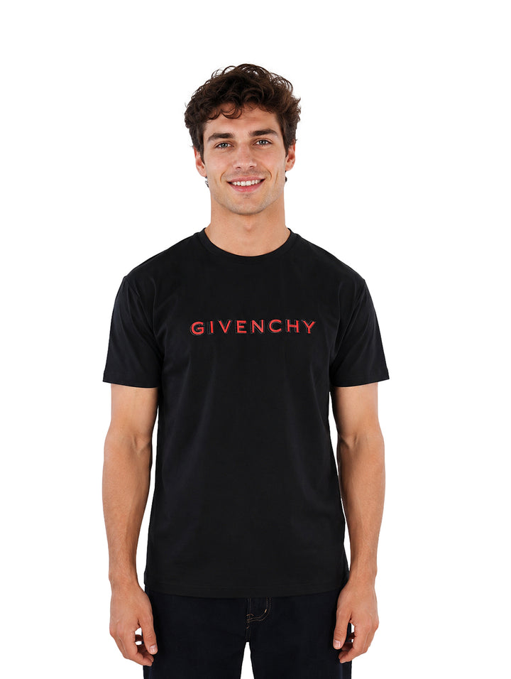 Hombre vistiendo una playera Givenchy de color negro con logotipo rojo en el pecho.