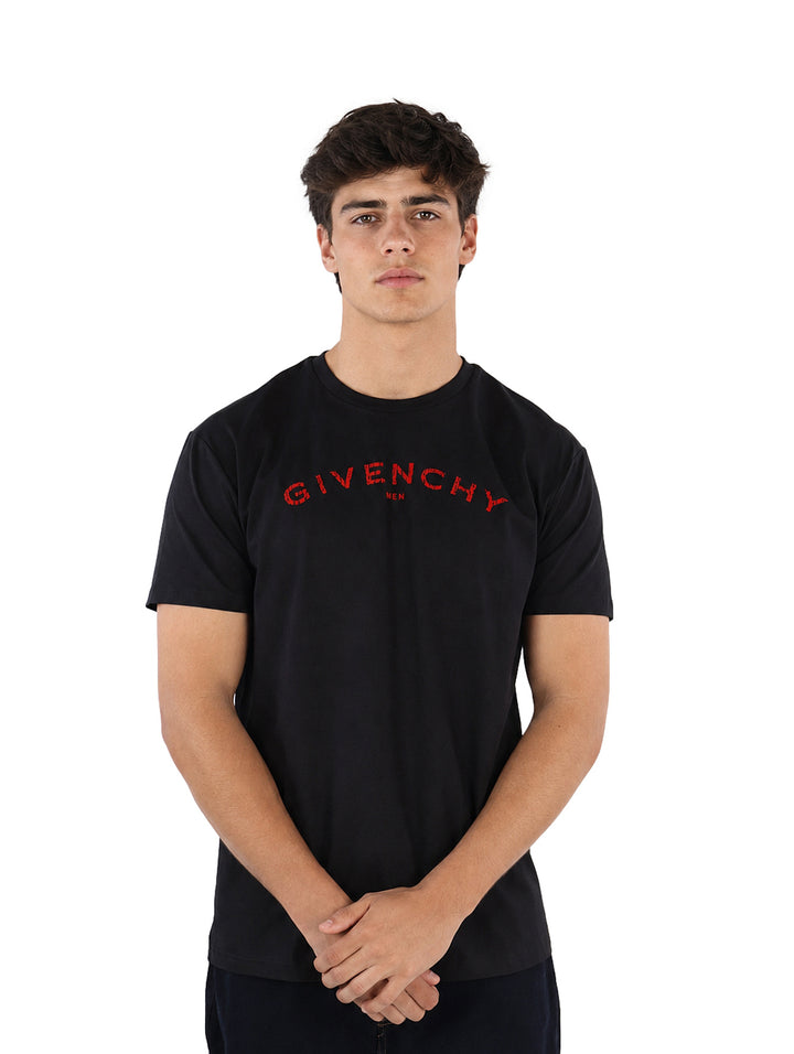Hombre vistiendo una playera Givenchy de color negro con letras rojas en el pecho.