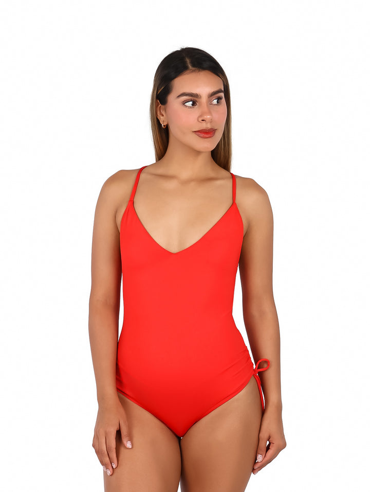 Mujer vistiendo un traje de baño enterizo color rojo fuego con cuello en V y tirantes delgados.