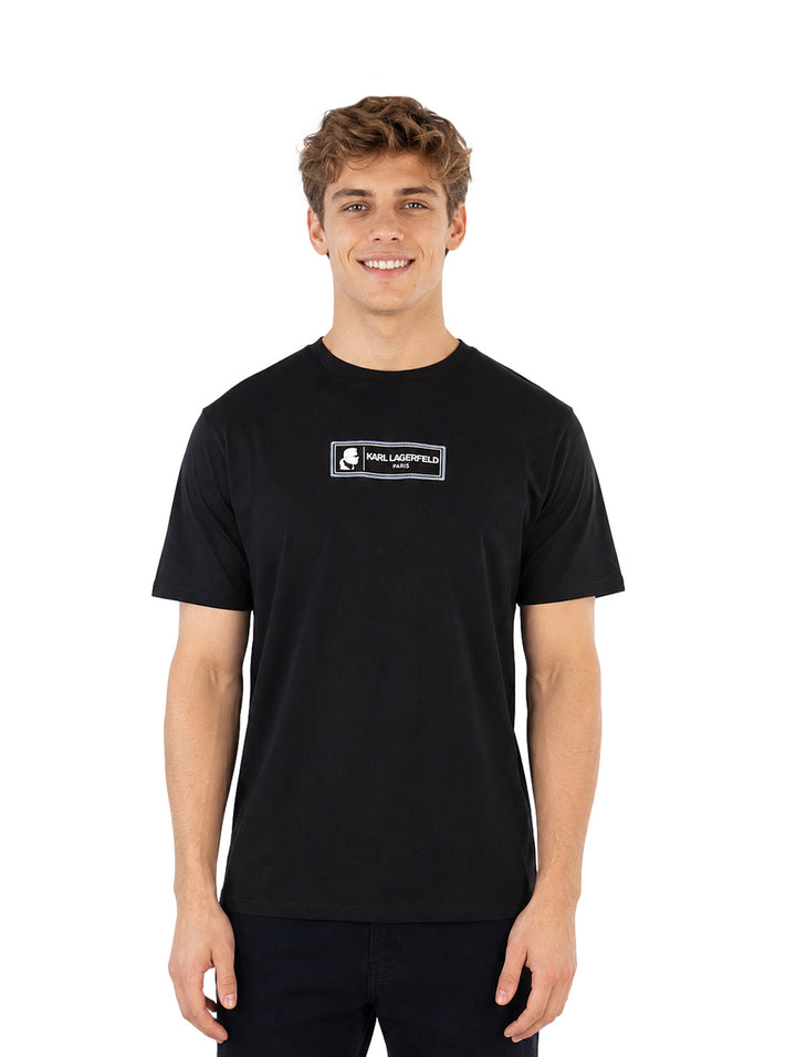 Hombre vistiendo playera negra de manga corta con logo de Karl Lagerfeld en el pecho.
