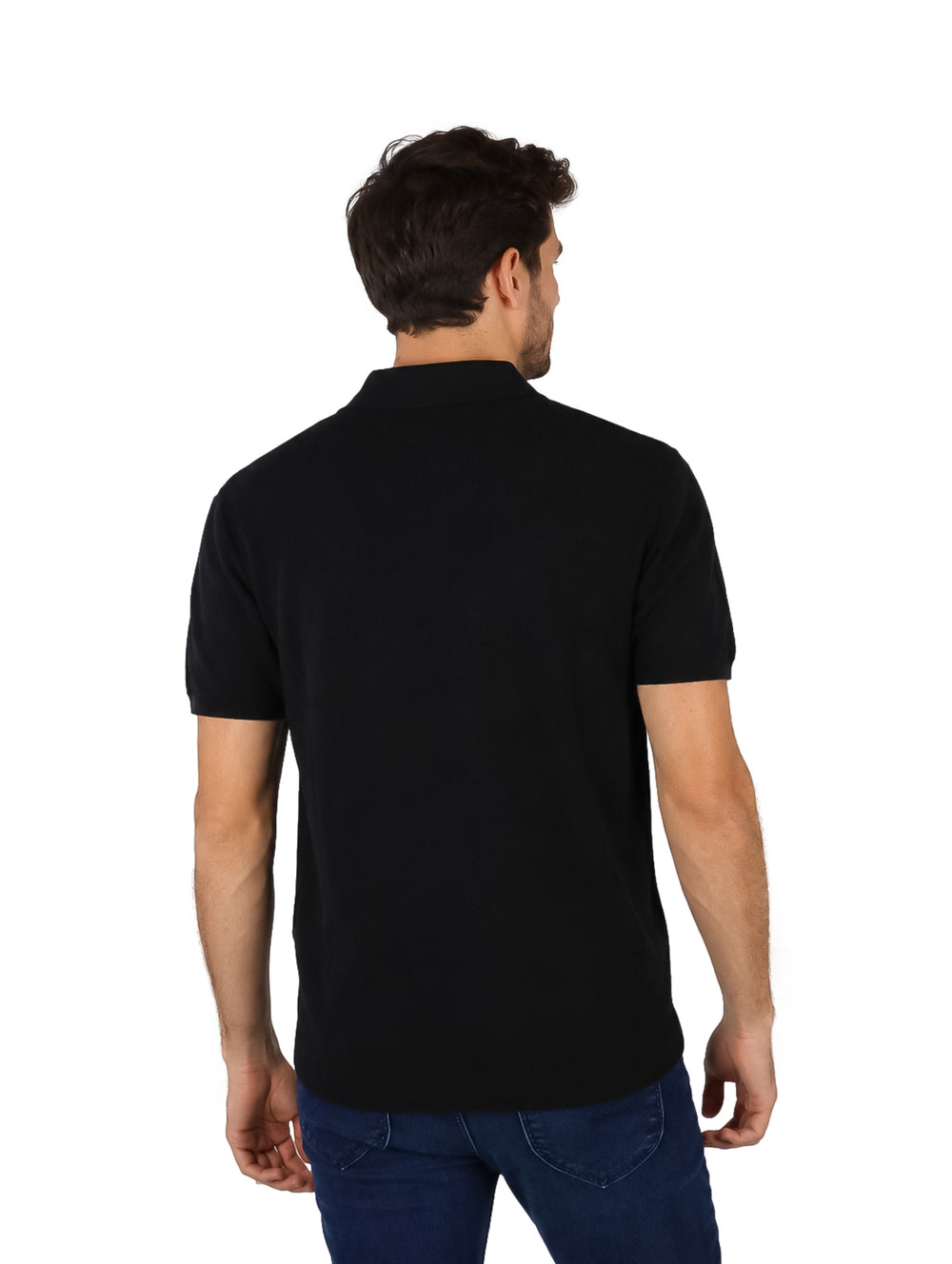 Hombre vistiendo una playera polo de color negro y pantalones azules.