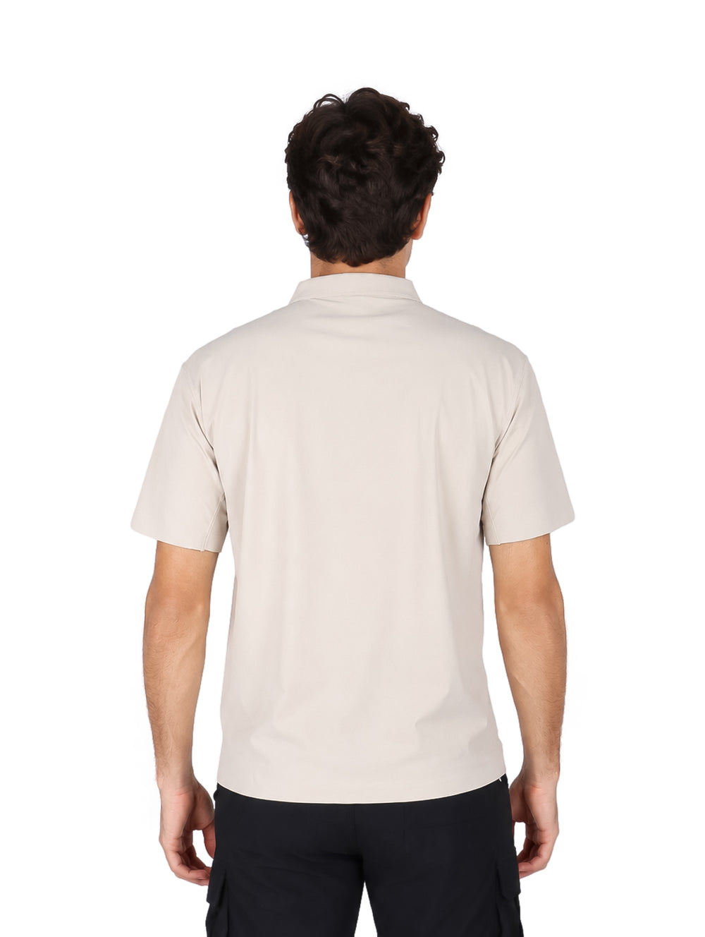 Hombre vistiendo una playera polo color beige de manga corta y pantalones negros.