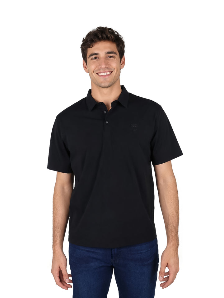 Hombre vistiendo una playera polo color negro de manga corta y pantalones vaqueros azules.