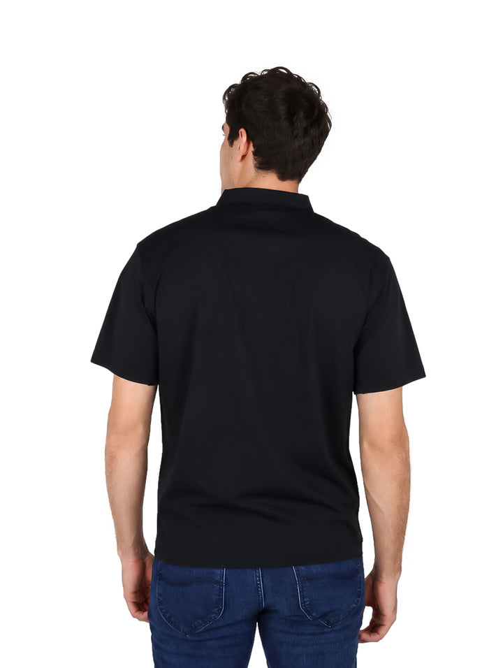 Hombre vistiendo una playera polo color negro de manga corta y pantalones vaqueros azules.