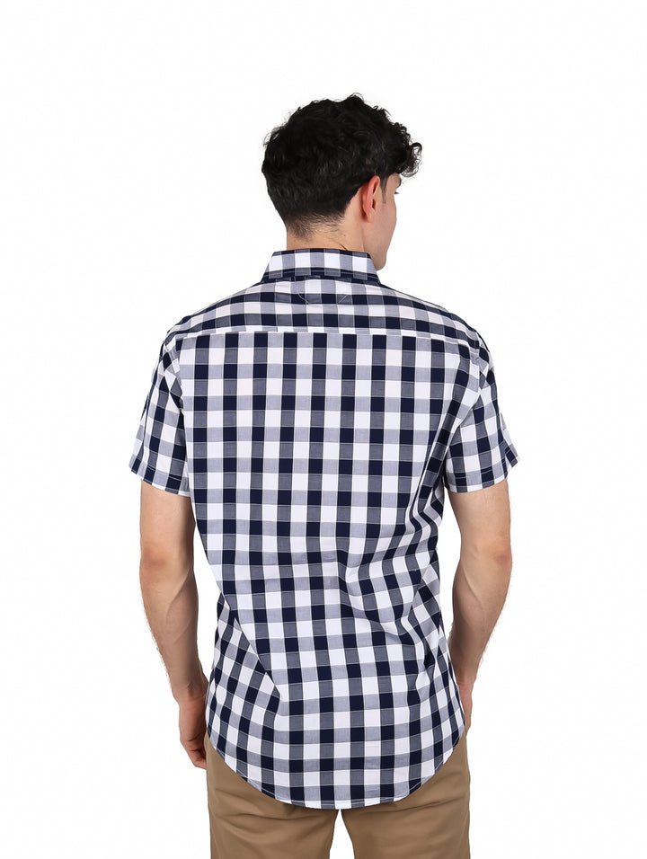Hombre vistiendo camisa de manga corta con estampado de cuadros en color marino y blanco.