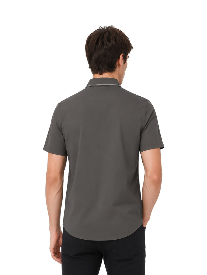 Hombre vistiendo una camisa de manga corta color olivo con detalle blanco en el cuello y pantalones negros.