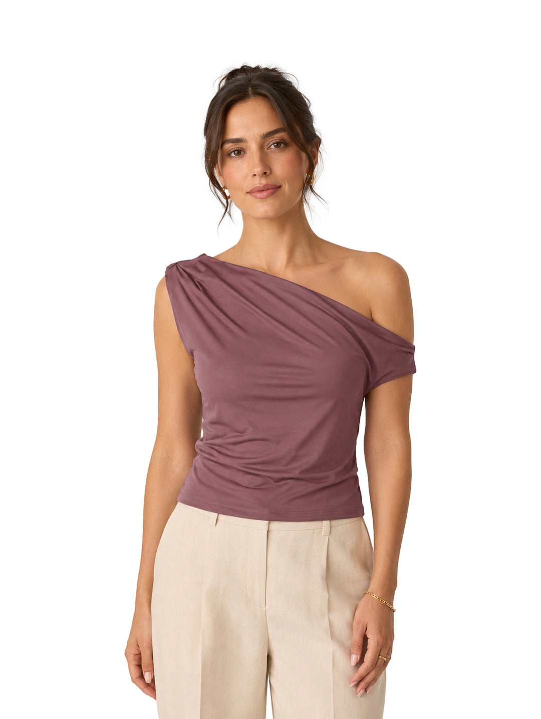 Mujer vistiendo una blusa morada asimétrica de un solo hombro y pantalones beige.