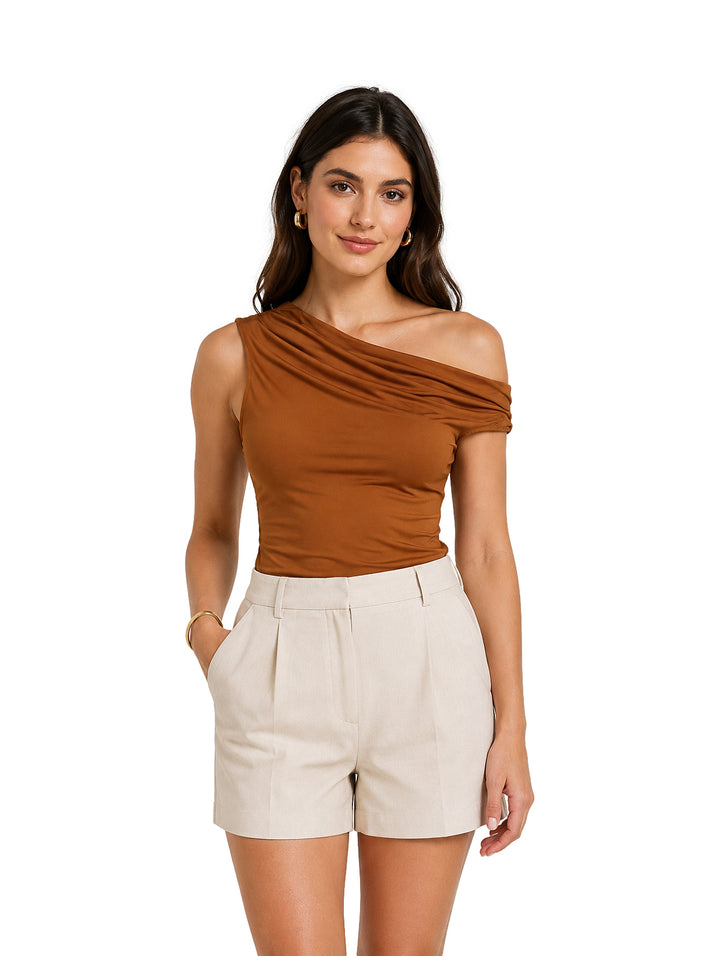 Mujer vistiendo blusa marrón de un solo hombro y shorts beige sobre fondo blanco.