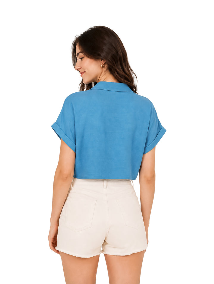 Mujer vistiendo blusa corta color azul anudada al frente y shorts blancos.