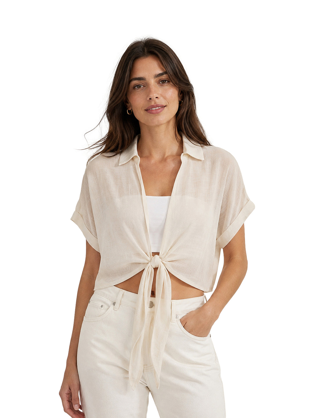 Mujer vistiendo blusa corta color blanco con cierre anudado al frente y pantalones blancos.