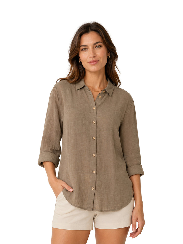Mujer vistiendo camisa marrón de botones y shorts beige sobre fondo blanco.