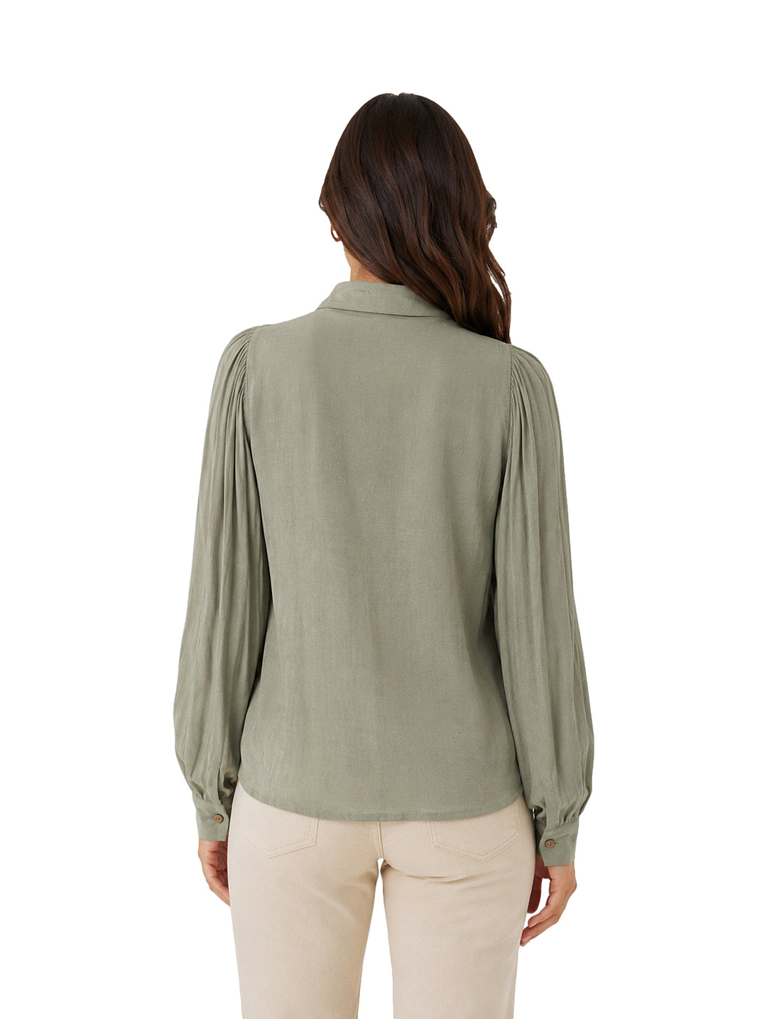 Mujer vistiendo camisa verde de manga larga con lazo en el cuello y pantalones beige.