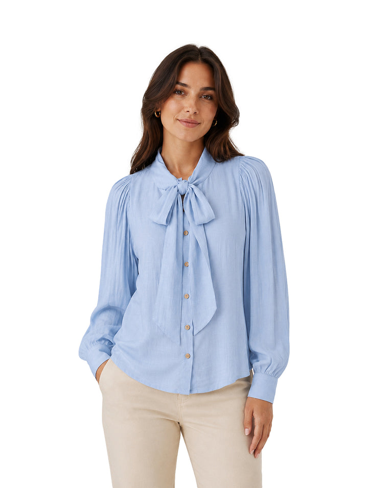 Blusa azul de manga larga con lazo al cuello y botones frontales.