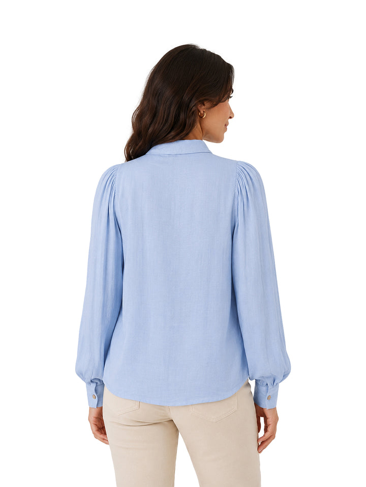 Blusa azul de manga larga con lazo al cuello y botones frontales.