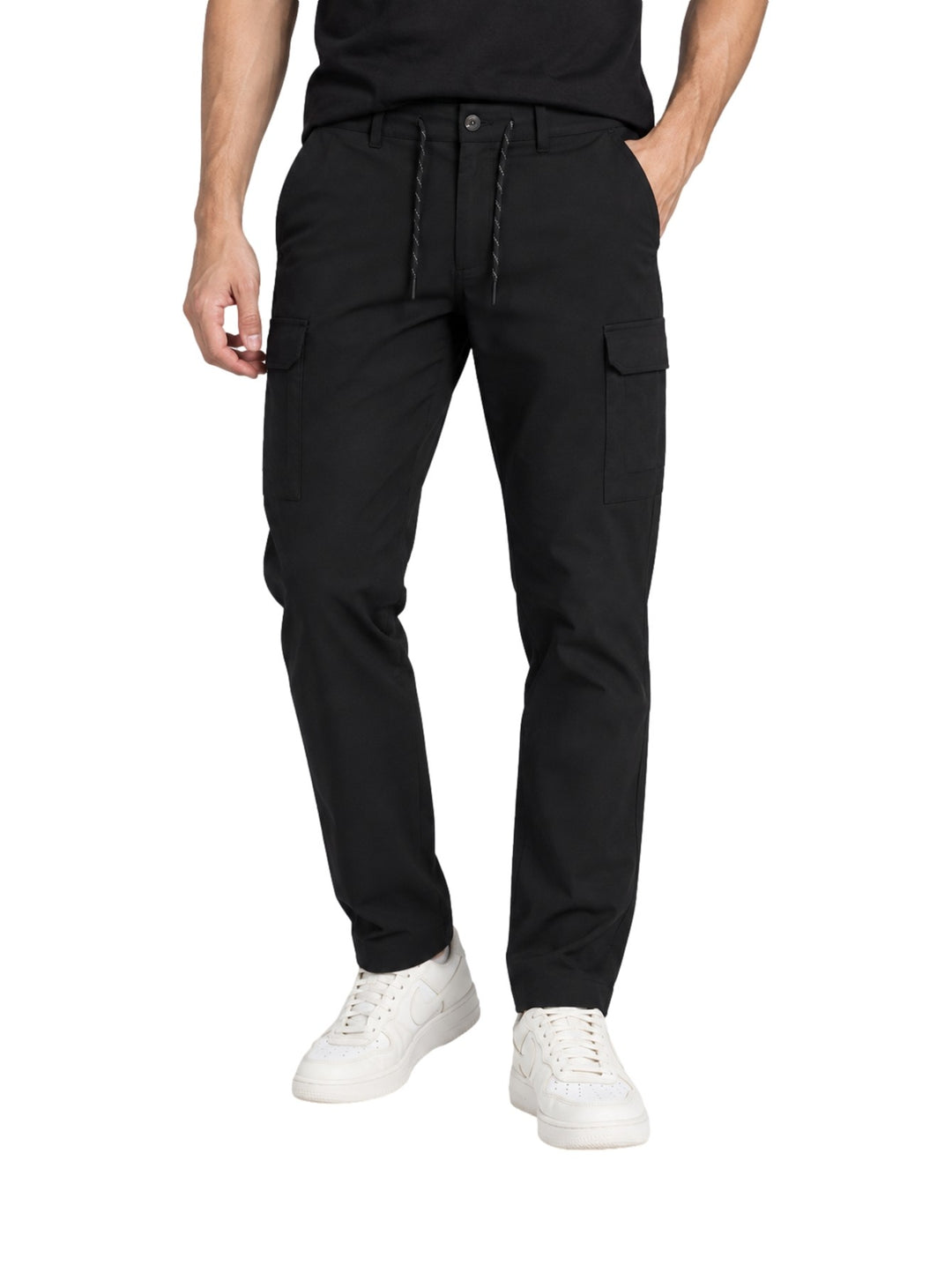 Hombre vistiendo pantalones cargo Columbia Trail color negro con bolsillos laterales y calzado blanco.