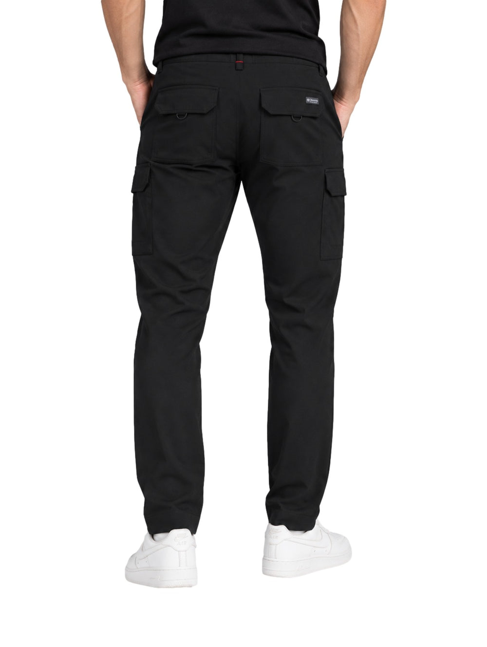Hombre vistiendo pantalones cargo Columbia Trail color negro con bolsillos laterales y calzado blanco.