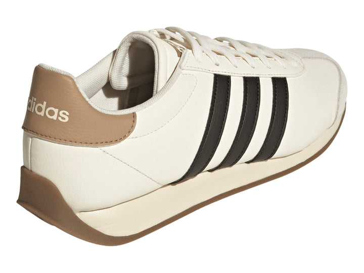 Tenis Adidas color blanco crema con tres franjas negras laterales y suela color café.
