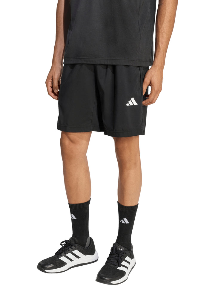 Hombre vistiendo pantalones cortos deportivos Adidas de color negro.