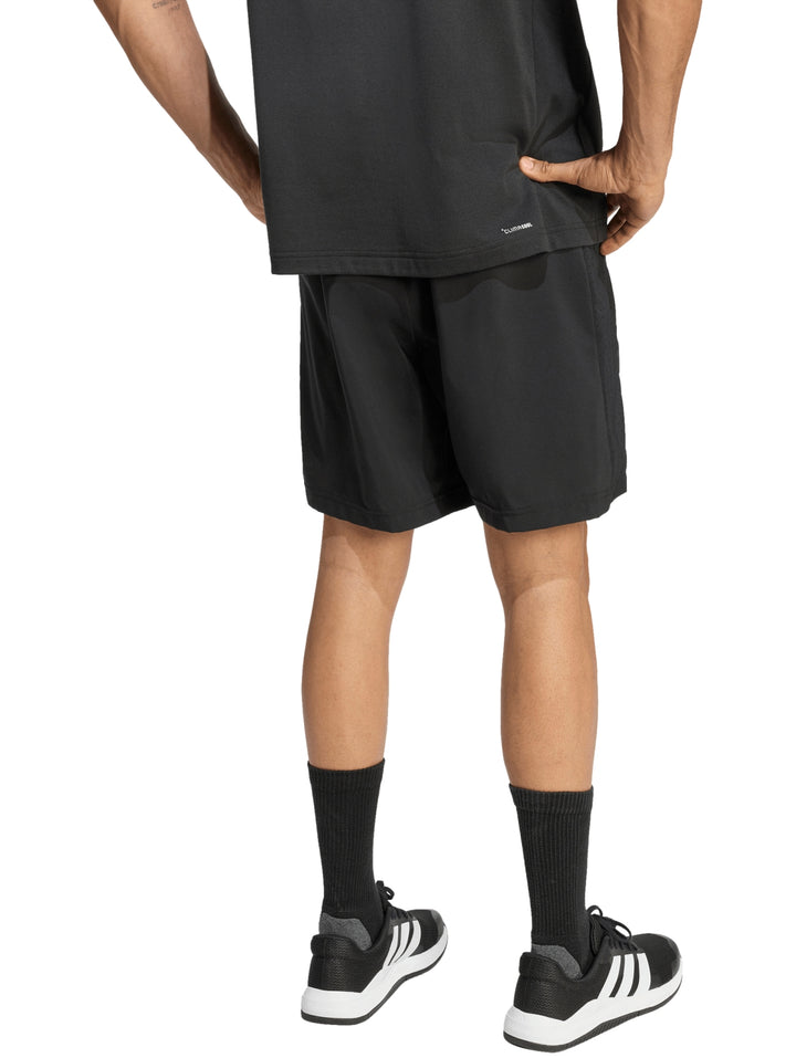 Hombre vistiendo pantalones cortos deportivos Adidas de color negro.