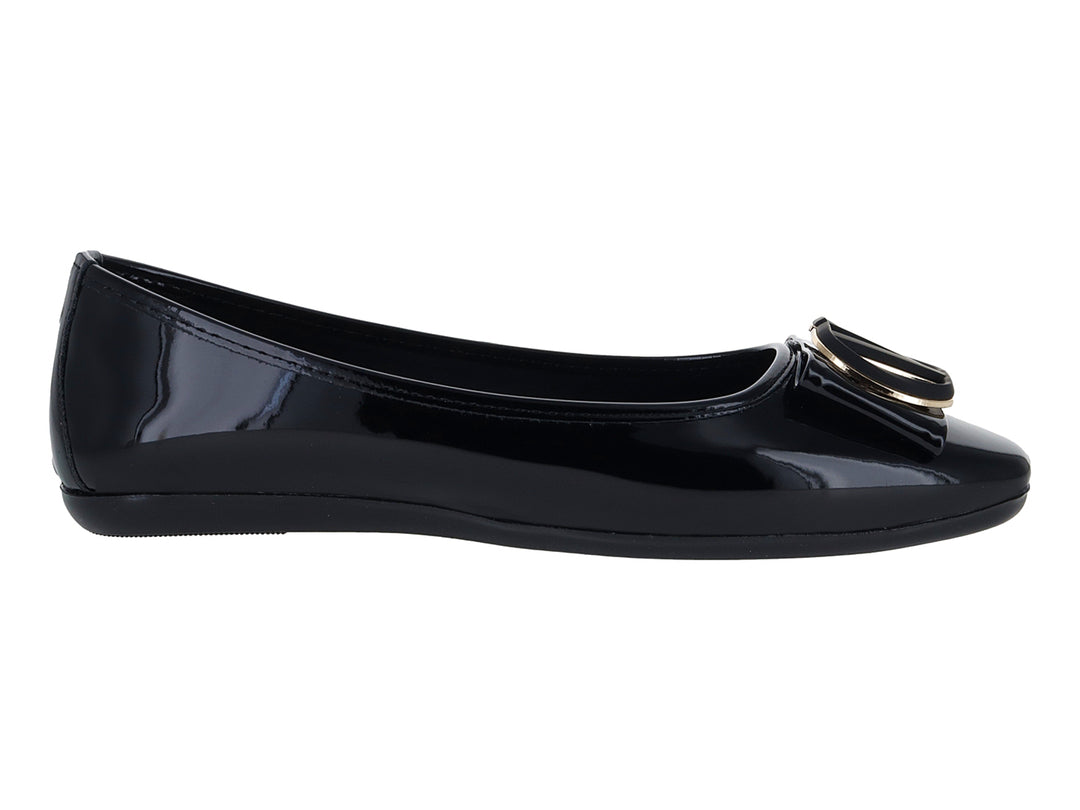 Zapato plano de charol negro con detalle de hebilla dorada en la punta.