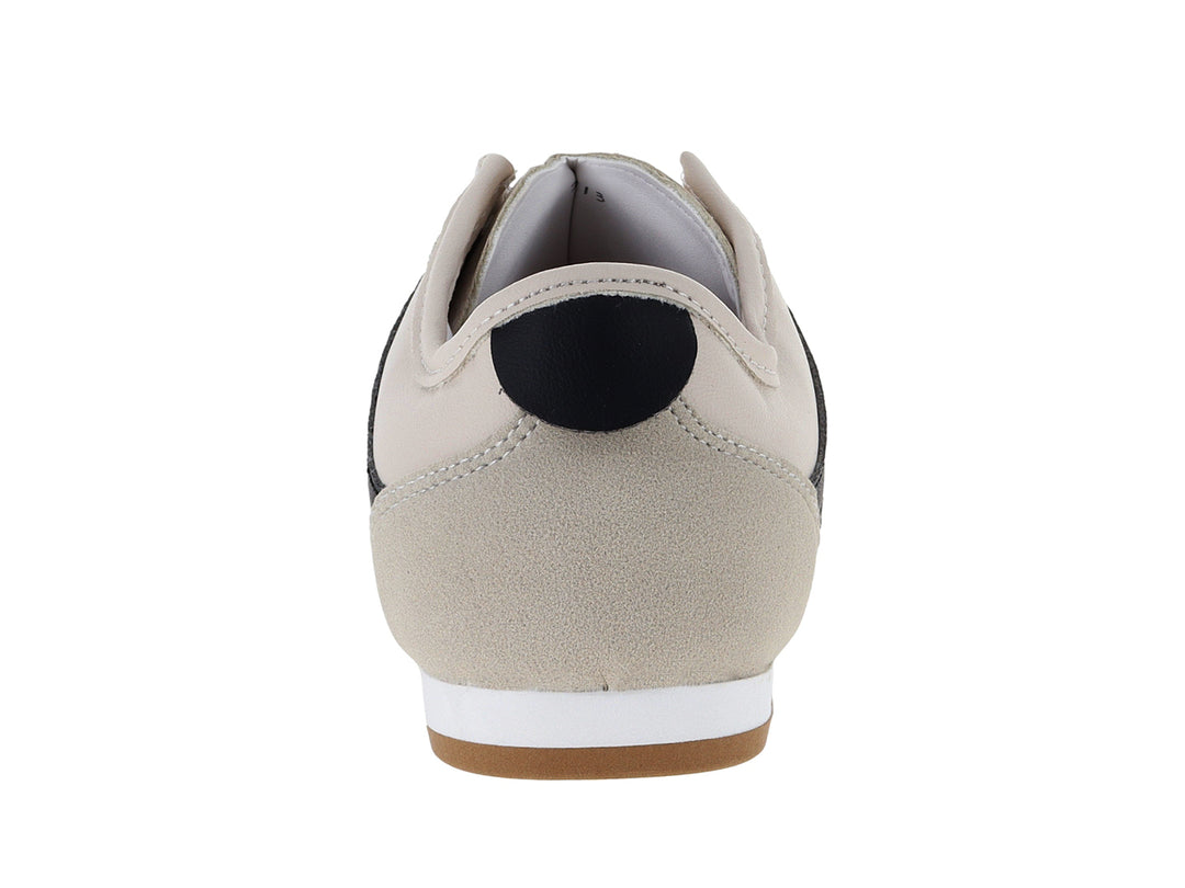 Tenis Andrax color latte con franjas negras y suela de goma marrón.