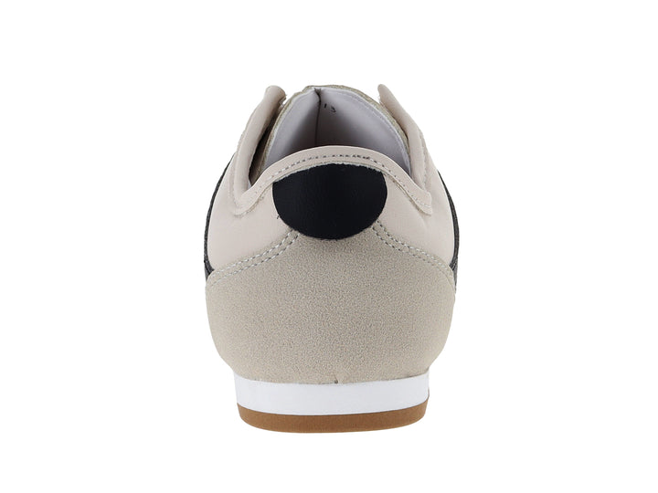 Tenis Andrax color latte con franjas negras y suela de goma marrón.