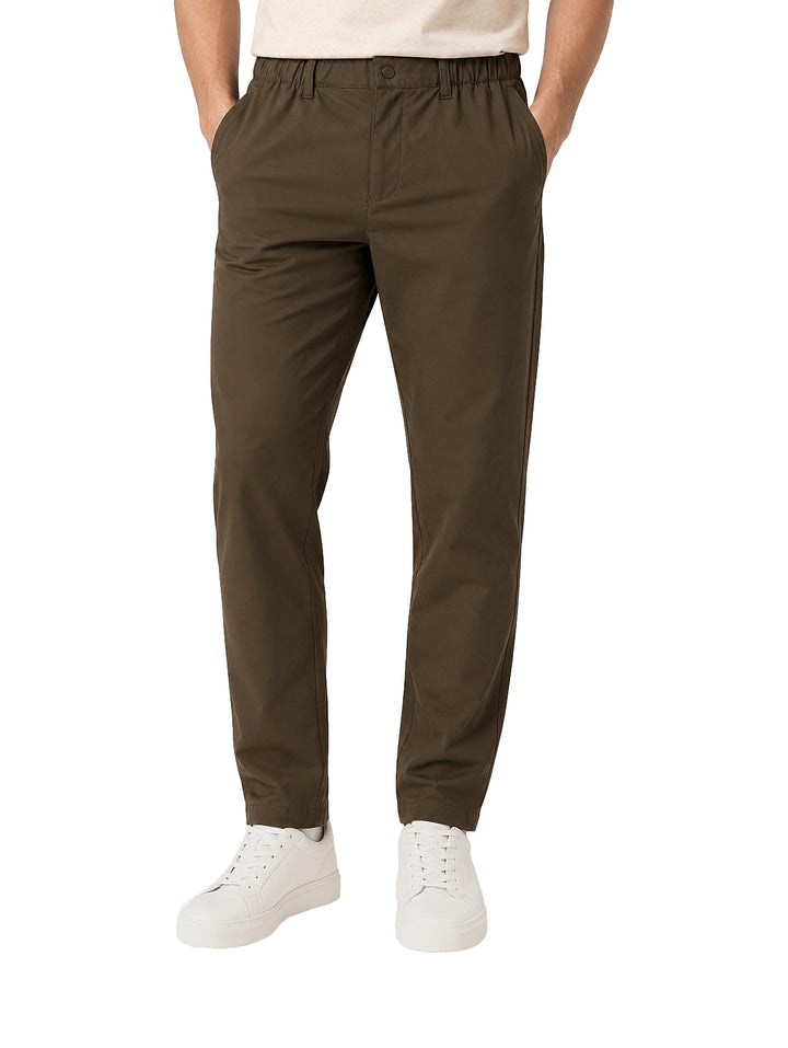 Hombre vistiendo pantalón color olivo oscuro de corte casual y tenis blancos.