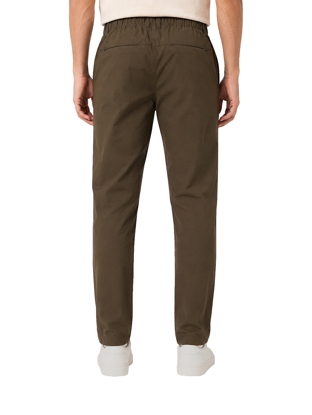 Hombre vistiendo pantalón color olivo oscuro de corte casual y tenis blancos.