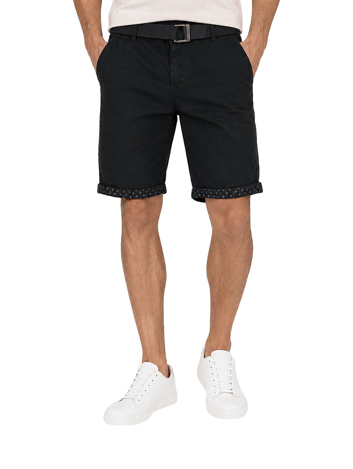 Hombre vistiendo bermuda color negro con cinto a juego y tenis blancos.