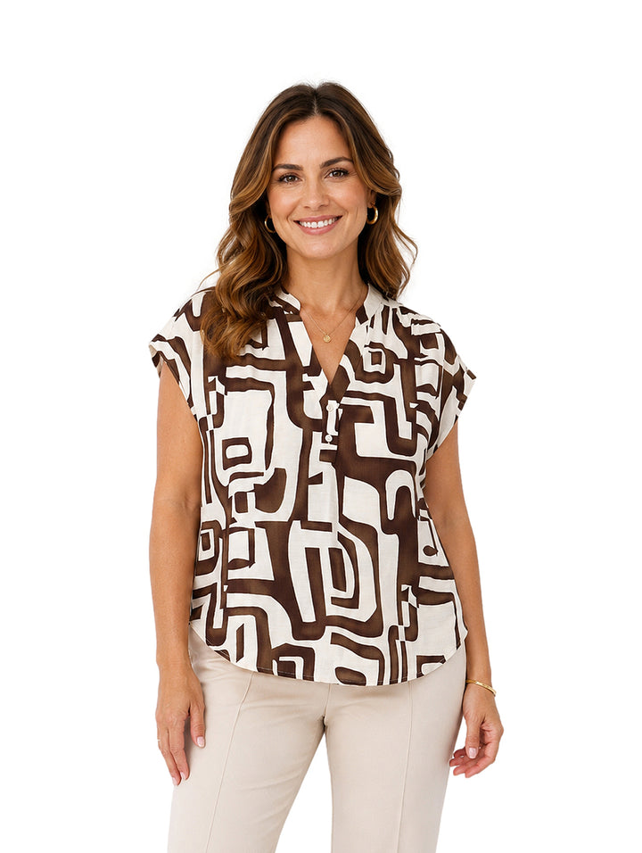 Mujer vistiendo blusa de manga corta con estampado abstracto en colores marrón y blanco.
