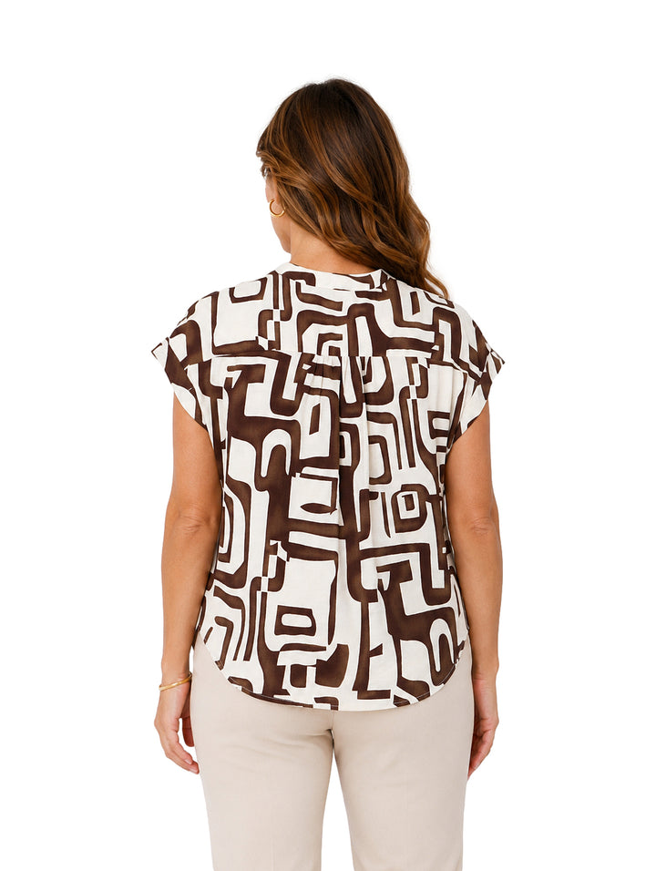 Mujer vistiendo blusa de manga corta con estampado abstracto en colores marrón y blanco.