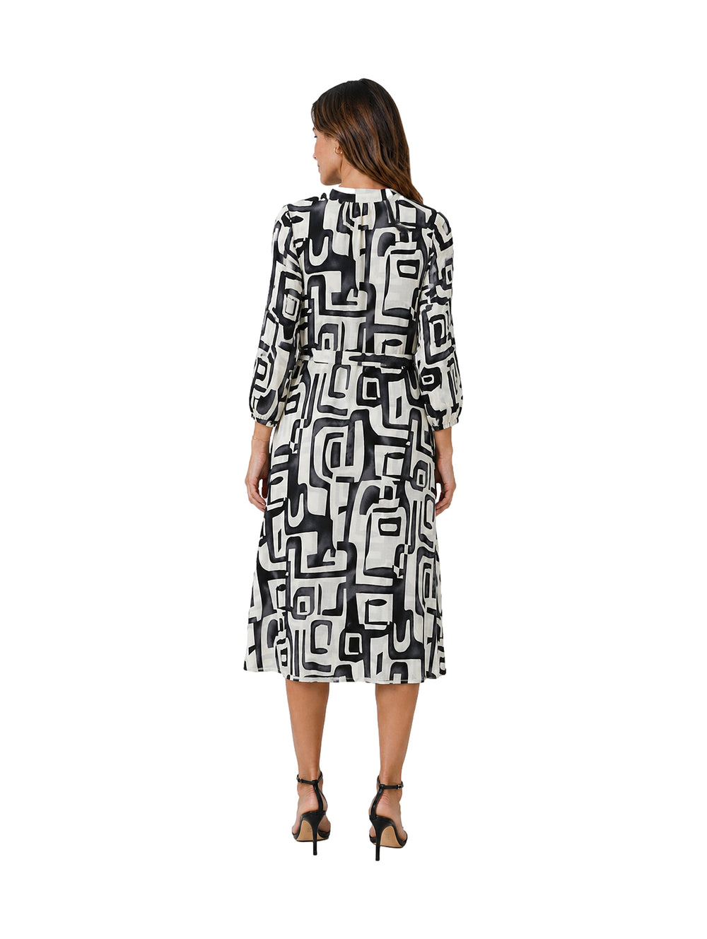 Mujer vistiendo un vestido midi de manga larga con estampado geométrico en blanco y negro.