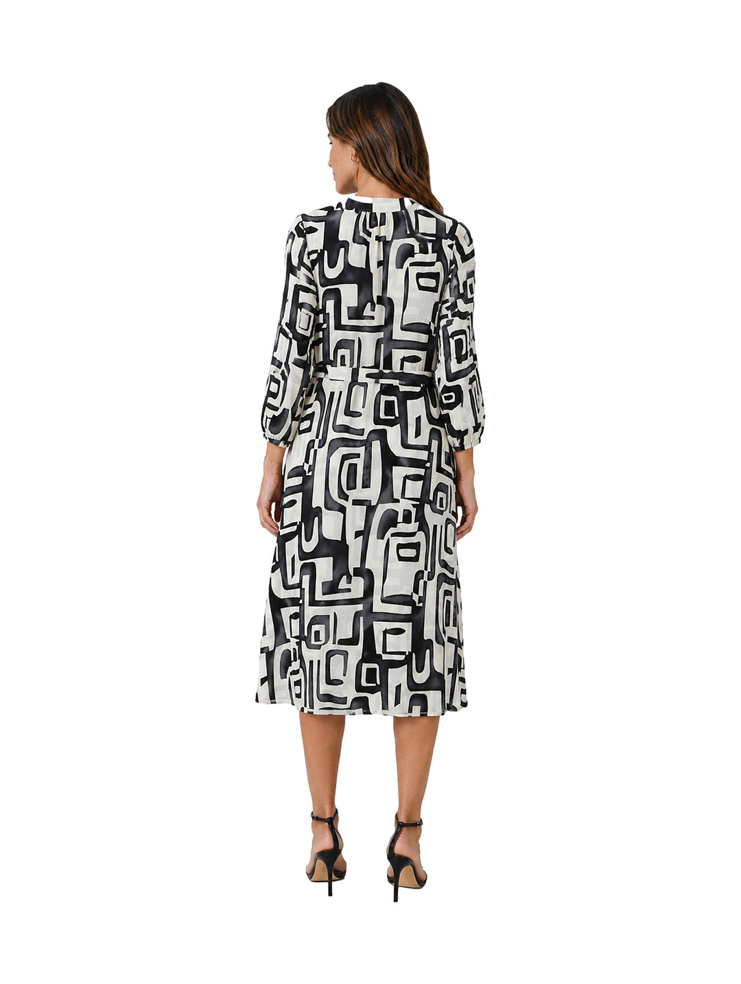 Mujer vistiendo un vestido midi de manga larga con estampado geométrico en blanco y negro.