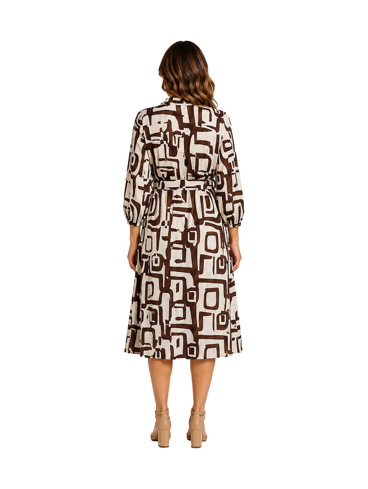 Mujer vistiendo un vestido midi marrón y blanco con estampado geométrico y cinturón.