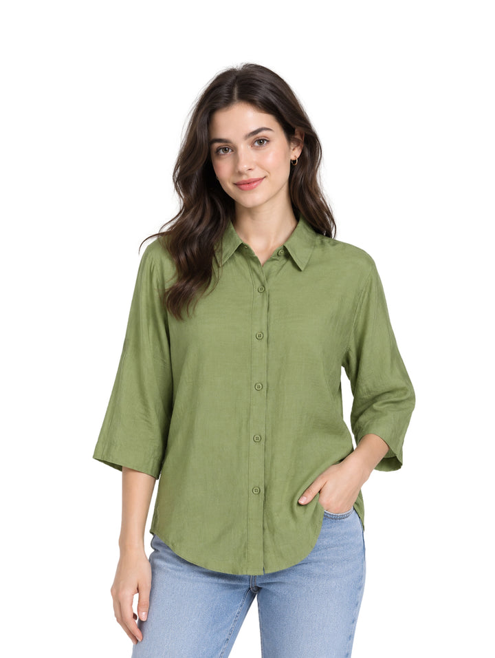 Mujer vistiendo una camisa verde de botones con mangas 3/4 y pantalones azules.